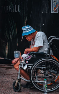 Rear view of man sitting on street in city