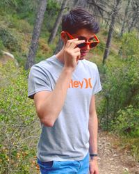 Young man wearing sunglasses standing on land