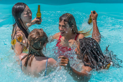 People from different ethnicities playing and stirring the water in a pool
