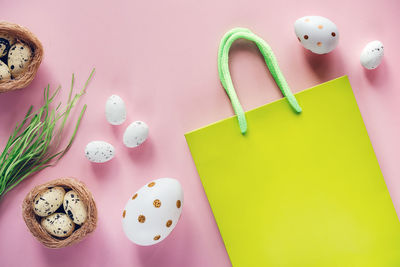 Easter shopping background with green shopping bag with easter eggs and bird's nest on pink