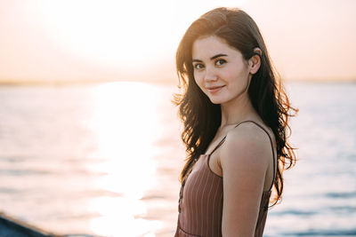 Portrait of young woman standing against sea