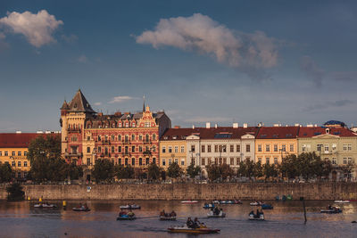 Boats in river against buildings in city