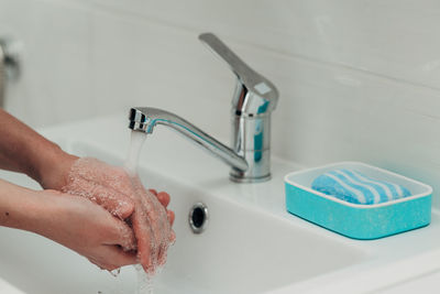 Cropped hand washing hands in sink