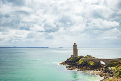 Lighthouse by sea against sky