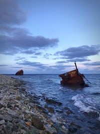 Abandoned boat on sea against sky