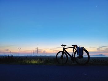 Bicycle parked against sky during sunset