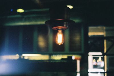 Low angle view of illuminated light bulb hanging from ceiling