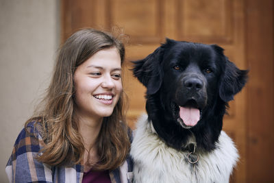 Portrait of teenager girl sitting with her czech mountain dog against against door of house.