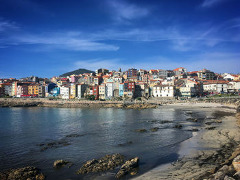 Buildings by river against sky