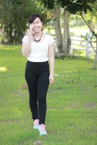 Full length of smiling young woman standing on field