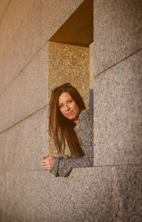 Portrait of smiling woman standing by wall