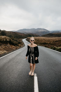 Woman standing on road against sky