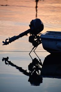 Silhouette person on boat in lake against sky during sunset