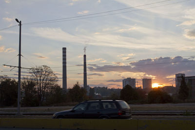 Cars on street against sky at sunset