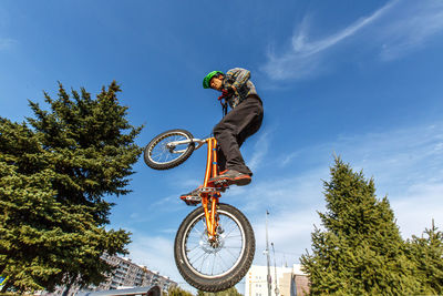 Low angle view of man performing bicycle stunt against sky