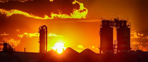 Oil refinery against cloudy sky during sunset