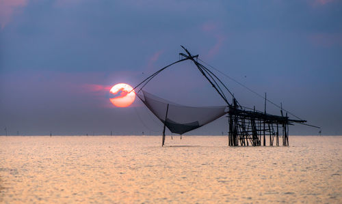 Lifeguard hut on land against sky during sunset