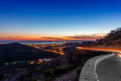 Illuminated road against sky during sunset