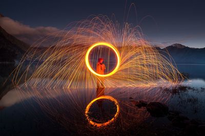 Light painting by lake against sky at night