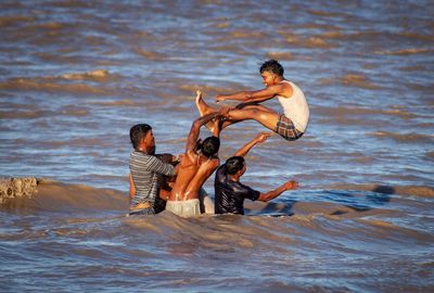 Full length of shirtless man surfing in sea