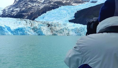 Rear view of man photographing iceberg