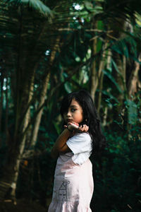 Girl looking away while standing on tree