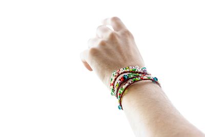 Cropped hand of person with bracelets against white background