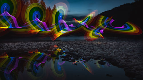 Multi colored illuminated rainbow over water at night