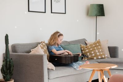 Young girl sat at home playing her guitar