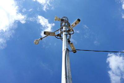 Low angle view of security cameras against blue sky