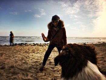 Young woman playing with dog at beach