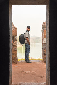 Portrait of young man standing against wall