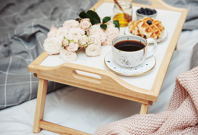 Romantic breakfast with coffee, waffles, gift box and rose flowers.