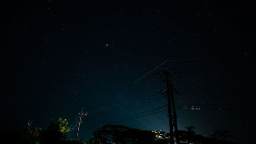 Low angle view of electricity pylon against sky at night