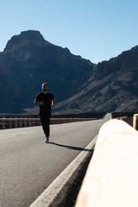 Rear view of man on mountain road against clear sky