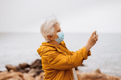 Side view of woman looking at sea against clear sky