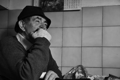Man smoking cigarette while sitting against tiled wall