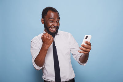 Young man using mobile phone against blue background