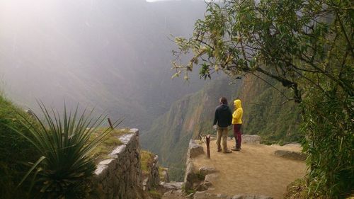 Rear view of men walking on footpath by mountain