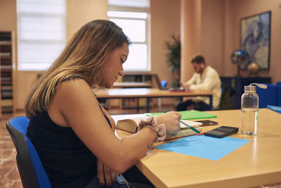 Side view of young woman sitting on table