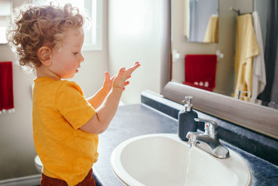  boy toddler washing hands in bathroom at home. health hygiene and morning routine for children. 