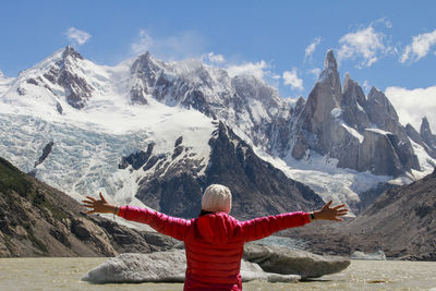 Rear view of woman standing on snowcapped mountains against sky