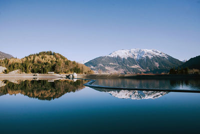 Reflection of mountains on calm lake against clear blue sky