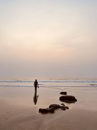 Silhouette man on beach against sky during sunset