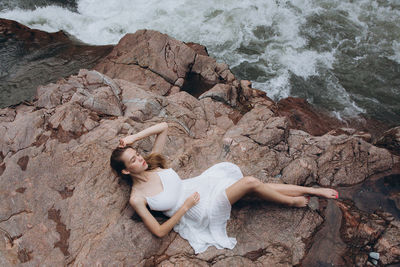 High angle view of woman relaxing on cliff by sea