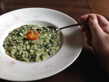 Cropped hand holding spoon over food served on table