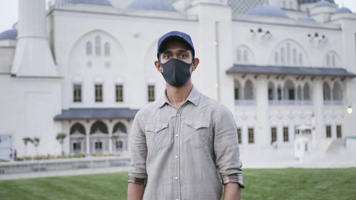 Portrait of young man standing against building