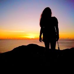 Silhouette people looking at sea against sky during sunset