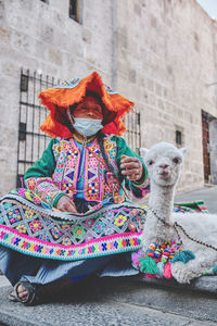 Peruvian woman in traditional clothes holding a baby llama in street arequipa, peru. selective focus