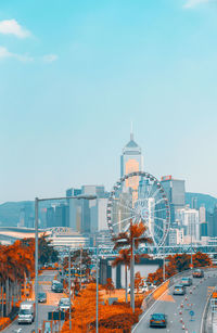 Ferris wheel and buildings in city against clear sky